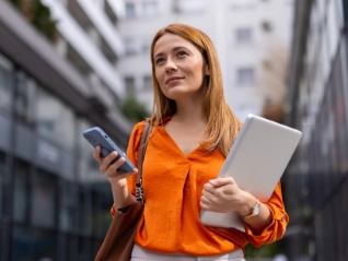 woman in orange shirt with mobile and laptop