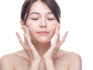 East Asian woman applying skincare to her face