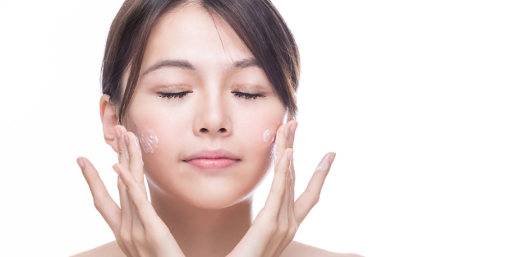 East Asian woman applying skincare to her face
