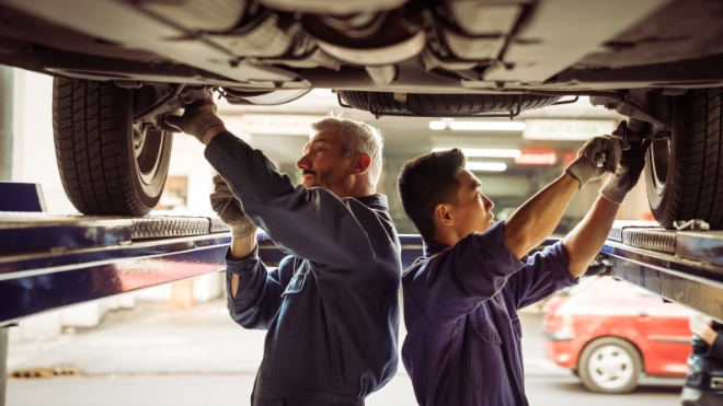 Two mechanics working underneath a car