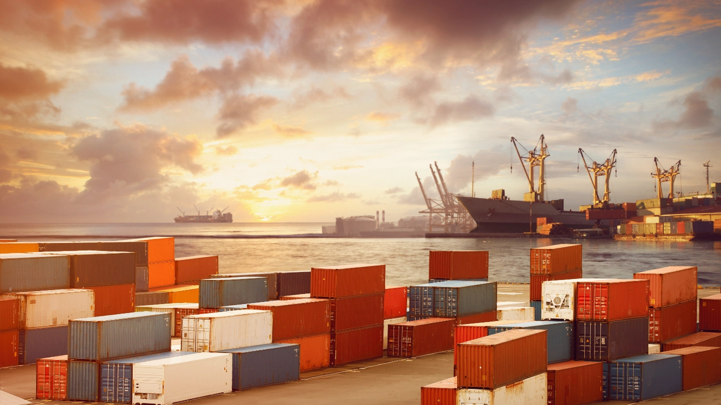 Shipping containers stacked up with sea in the background image