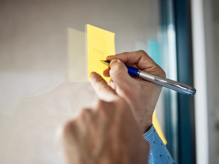 hands writing on post it note